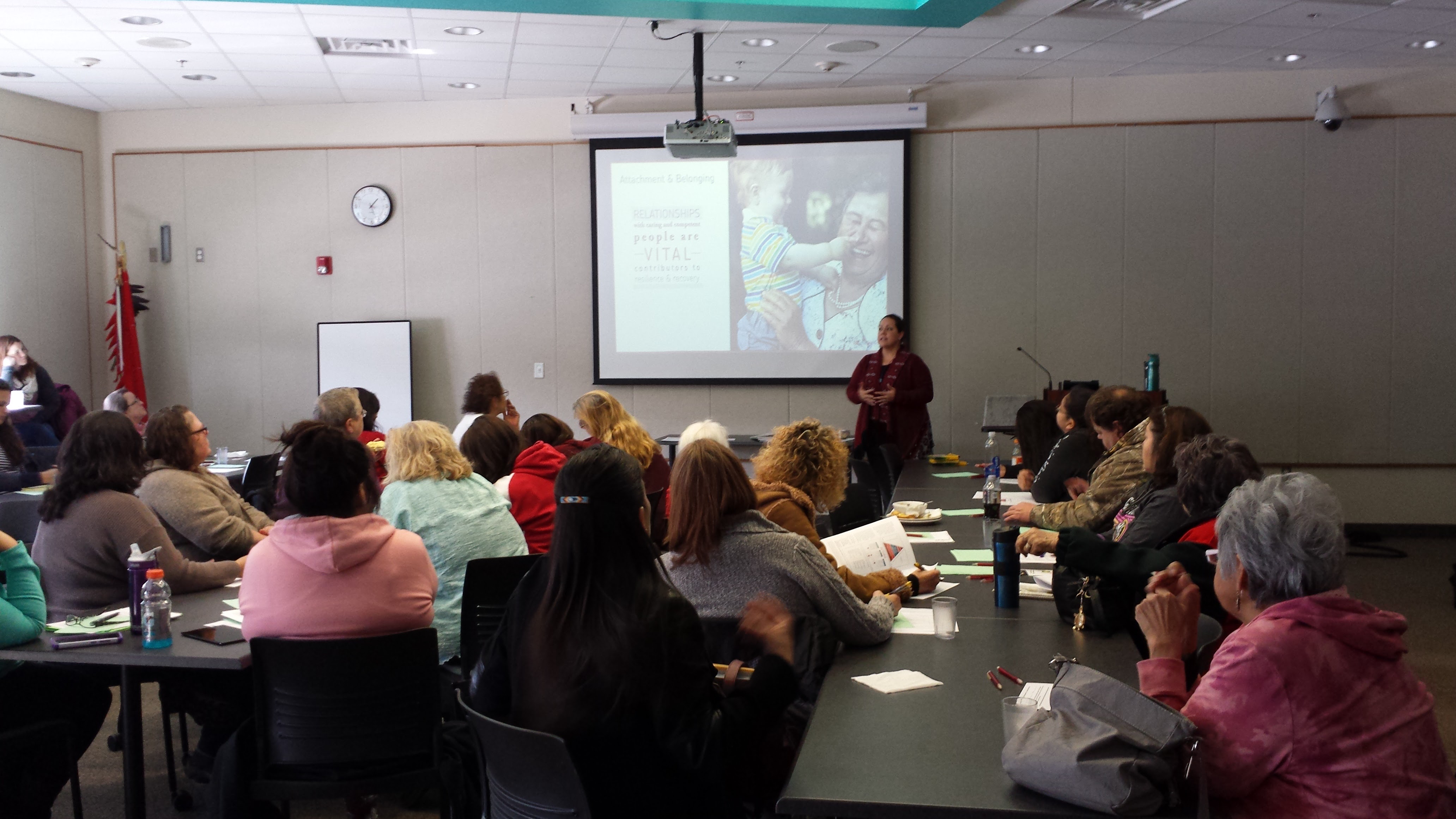 A room full of people receiving a training from a teacher. 